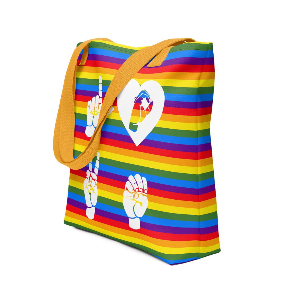 An angled view of a pride rainbow colored tote bag with a yellow handle and the word LOVE in white ASL fingerspelling design