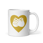 White mug with a gold coloured heart design featuring the BSL sign for Love embedded in it. The mug handle is on the right hand side of the mug.