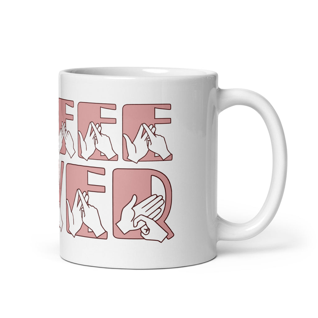 White mug featuring the phrase Coffee Lover written in BSL Fingerspelling and Text wrapping around the mug in pink. The mug handle is on the right hand side of the mug.